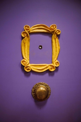 Close-up of purple door with peephole in the middle of gilt decoration